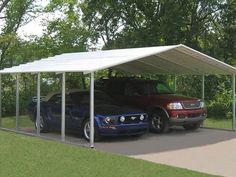 two cars are parked under a carport in the driveway next to trees and grass