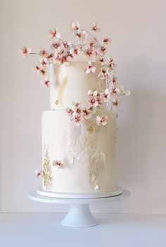 a three tiered cake with white frosting and pink flowers