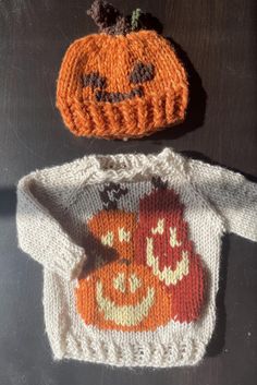 two knitted pumpkin sweaters sitting next to each other