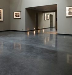 an empty room with pictures on the wall and flooring in it, all lit up by lights