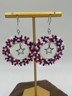 Show your love for the USA with these beautiful red, white and blue Miyuki seed bead earrings, with an open star charm hanging in the center. They are the perfect accessory for your 4th of July barbecue! Handcrafted earrings created using the brick stitch technique boast intricate designs and vibrant colors.  Width: 1.5" Drop: 2" Each pair of earrings is handmade, so slight variations may occur, adding to their unique charm.  Treat yourself or someone special to these gorgeous beaded hoop earrin Patriotic Multicolor Dangle Jewelry, Patriotic Adjustable Dangle Jewelry, Patriotic Drop Earrings Jewelry Gift, Patriotic Dangle Jewelry For Gifts, Nickel Free Dangle Jewelry For 4th Of July, Handmade Patriotic Dangle Earrings, Handmade Patriotic Drop Earrings, Patriotic Nickel-free Earrings For Gift, Handmade Blue Earrings For 4th Of July