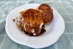 two pastries on a white plate covered in sauce