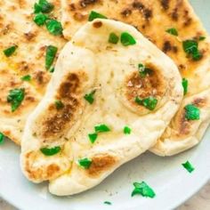 two flat breads on a white plate with green garnish