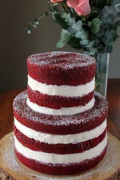 a three layer red velvet cake with white frosting