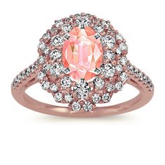 an oval cut pink diamond surrounded by white diamonds in a rose gold halo style ring