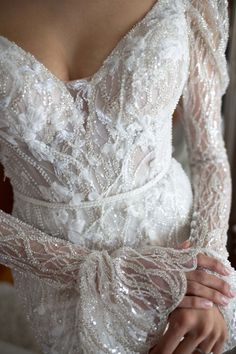 a woman wearing a wedding dress with long sleeves