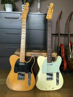 three guitars lined up next to each other on the floor in front of a wall