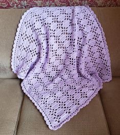 a purple crocheted blanket sitting on top of a couch