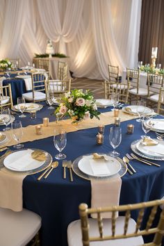 the table is set with white and blue linens, gold place settings, and flowers