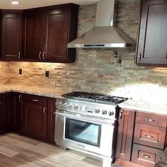 a kitchen with wooden cabinets and stainless steel stove top oven in the center, surrounded by wood flooring