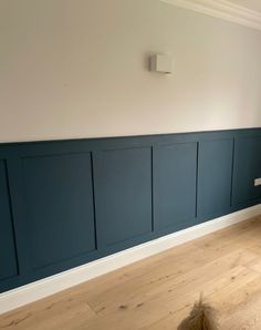 an empty room with wood flooring and blue paneling on the walls, along with a radiator