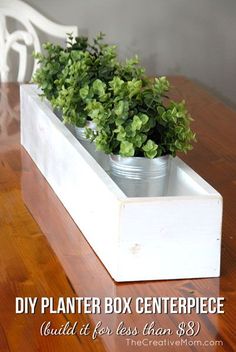 a white planter filled with green plants on top of a wooden table