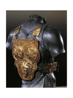 the back of a bronze statue with an ornate mask on it's chest