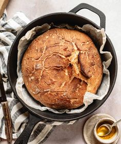 a loaf of bread in a cast iron skillet on a white and black towel