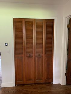 an empty room with wooden doors and hard wood flooring