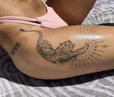 a woman laying on top of a bed with a tiger tattoo on her arm and leg