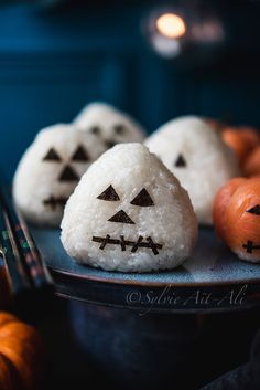 there are some rice balls decorated like jack - o'- lanterns on the plate