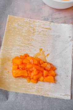 chopped up carrots sitting on top of a wooden cutting board next to a bowl