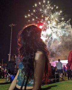 a woman looking at fireworks in the night sky with people standing around her and watching