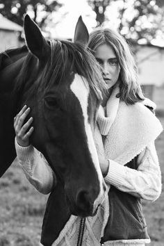 a woman standing next to a brown horse