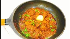 a pan filled with meat and sauce on top of a stovetop next to a spatula