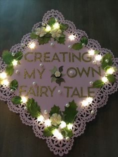 a sign that says creating my own fairy tale with lights around it and flowers on the side