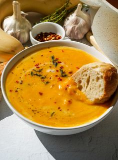 a bowl of soup with bread and garlic on the side