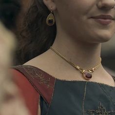 a close up of a woman wearing a necklace and earrings