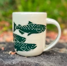 a white coffee mug with green fish on it