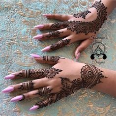 two hands with henna tattoos on them, one is pink and the other is black