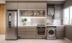 a modern kitchen with stainless steel appliances and wood paneling on the walls, along with a washer and dryer