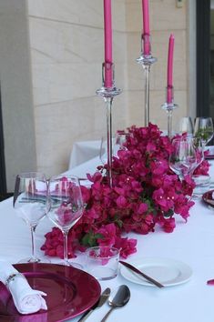 the table is set with pink flowers and wine glasses