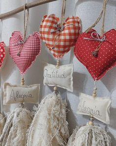 several heart shaped pillows hanging on a wall with name tags attached to the strings and tassels