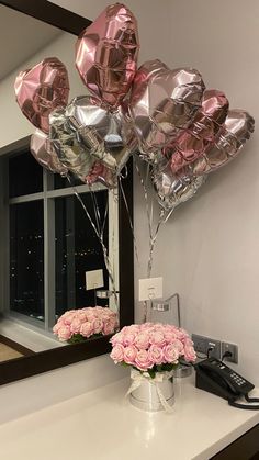 pink flowers and balloons are on the counter in front of a mirror