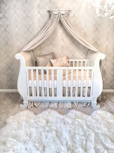 a white crib in the corner of a room with a chandelier above it