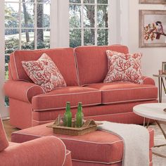 a living room with red couches and pillows on the floor next to a coffee table