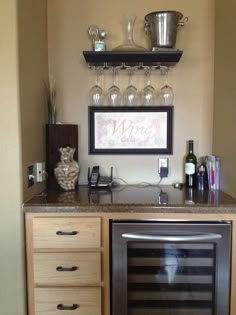 a kitchen with wine glasses and bottles on the shelf above the stove top, next to an empty wine glass holder