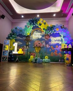 a birthday party with balloons and decorations on the wall, in front of a backdrop