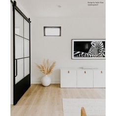 a living room with white walls and wood flooring has a zebra painting on the wall