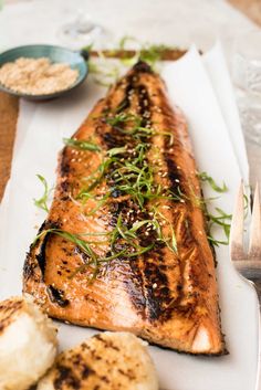 grilled salmon and potatoes on a white plate with silverware next to the plate