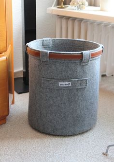 a grey felt basket sitting on the floor next to a radiator