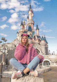 a woman sitting on top of a rock in front of a castle