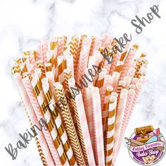 pink and gold striped paper straws are stacked on top of each other in front of a marble background