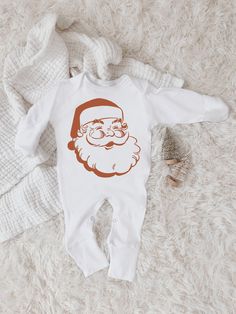 Celebrate Christmas with this sweet  bodysuit featuring a burnt red-orange Santa head. This sweet piece is the perfect light layer for baby. The design is printed on 100% cotton 7.2 oz . Please refer to the labeled picture (photo 3) for the apparel type. Sleeper Item has optional mitten and footies that can be folded. The classic baby bodysuit comes in long and short sleeves. This piece is a sturdy material, cozy soft and perfect for staying cuddly. This baby bodysuit is a sturdy material, cozy soft and perfect for staying cuddling. Please note: the sleeper apparel type comes in three options. Check out the third picture with labeled apparel type options.This baby bodysuit is a sturdy material, cozy soft and perfect for staying cuddling.  This product is handprinted using nontoxic, water-b Christmas Bodysuit, First Christmas Baby, Christmas Pj, Baby First Christmas, Santa Head, The Sleeper, Santa Shirt, Burnt Red, Baby Christmas Outfit