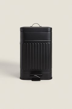 a black trash can sitting on top of a white surface