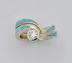 a gold ring with blue and white stripes on it, featuring a single diamond in the center