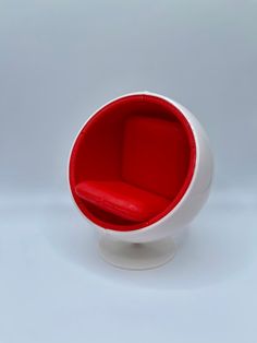 a red and white ball chair sitting on top of a white table next to a wall