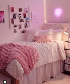 a bed with pink blankets and pillows in a room that has pictures on the wall