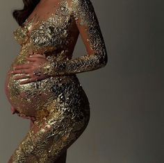 a pregnant woman in gold dress posing for the camera