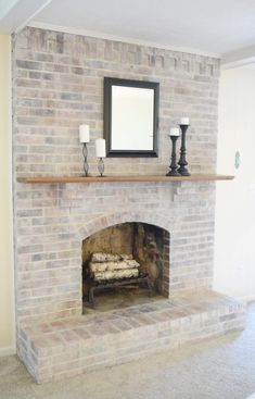 a brick fireplace with candles and a mirror above it in a room that has carpeted floors